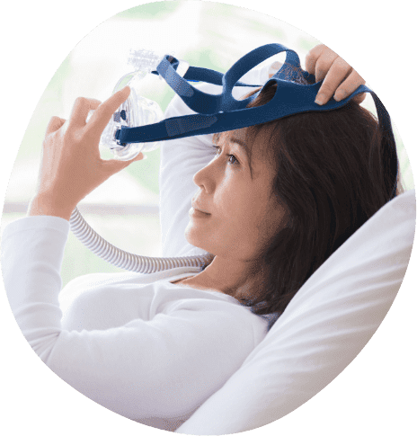 Woman in bed placing a C P A P mask over her face