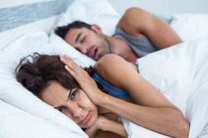 man snoring and woman covering her ears