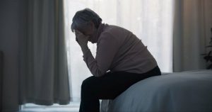 woman sitting on her bed feeling depressed