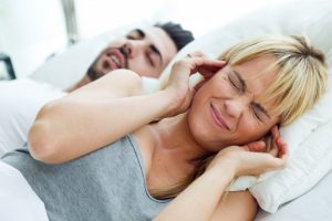 woman covering her ears because of snoring